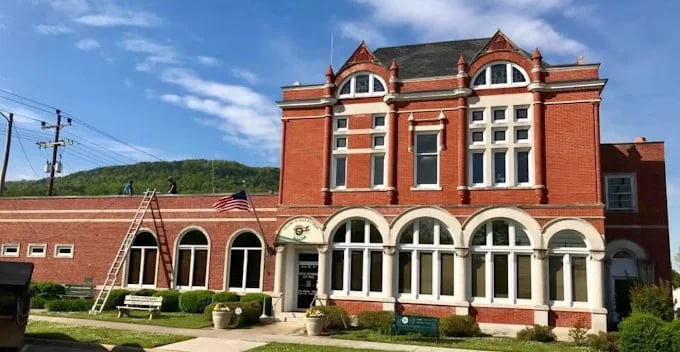 Historic red brick municipal building with arched windows and American flag