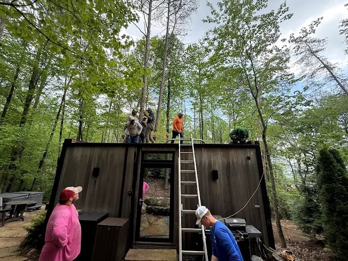 People climbing and standing on wooden shed in forest