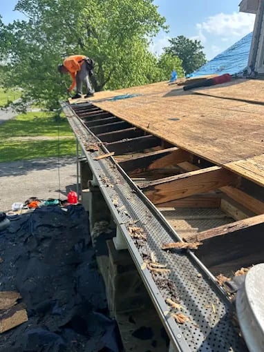Worker replacing roof shingles on a residential house on a sunny day
